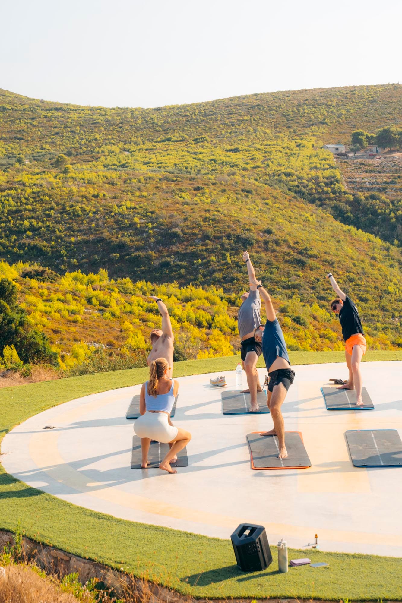 A coach leading a group through a stretch session on an outdoor deck